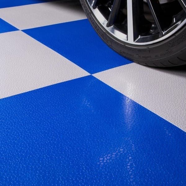 Catalog close-up of a vehicle tire on Blue and pale gray Smooth Flex Nitro tiles with straight checkerboard seams.
