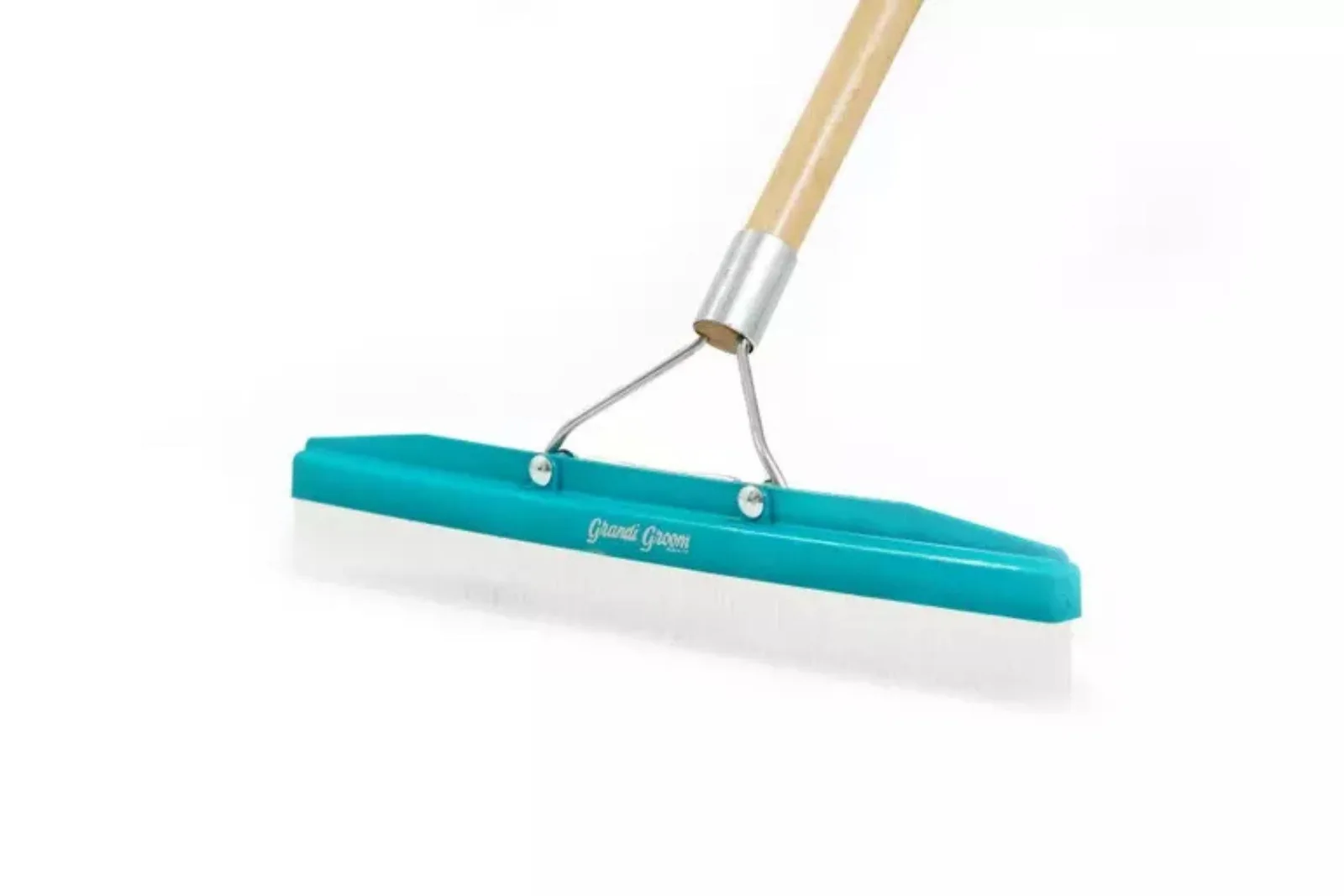 A close-up shot of a Grand Groom brand artificial turf rake, showing the white plastic bristles and long handle used to loosen and maintain artificial grass and synthetic turf.